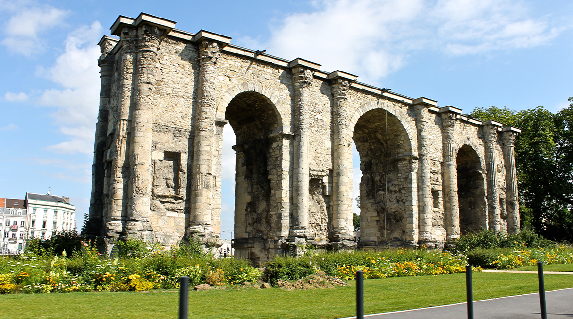 Ancient Roman archway under a blue sky with clouds